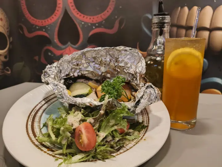 Fresh salad plate with a golden beverage at the table