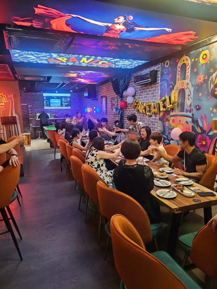 Long dining room full of guests under colourful lighting